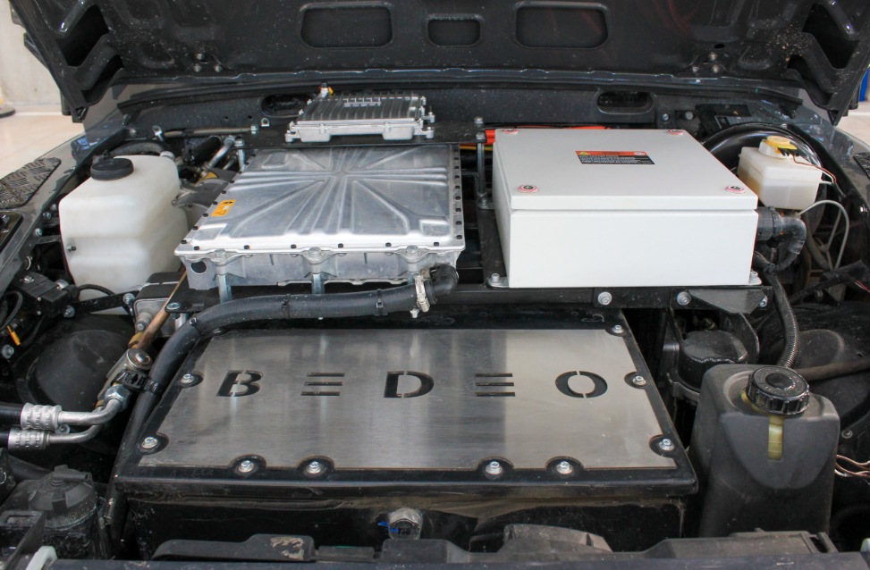 Under the bonnet of the Monarch Defender, showing a battery with a silver plaque covering the top with BEDEO engraved